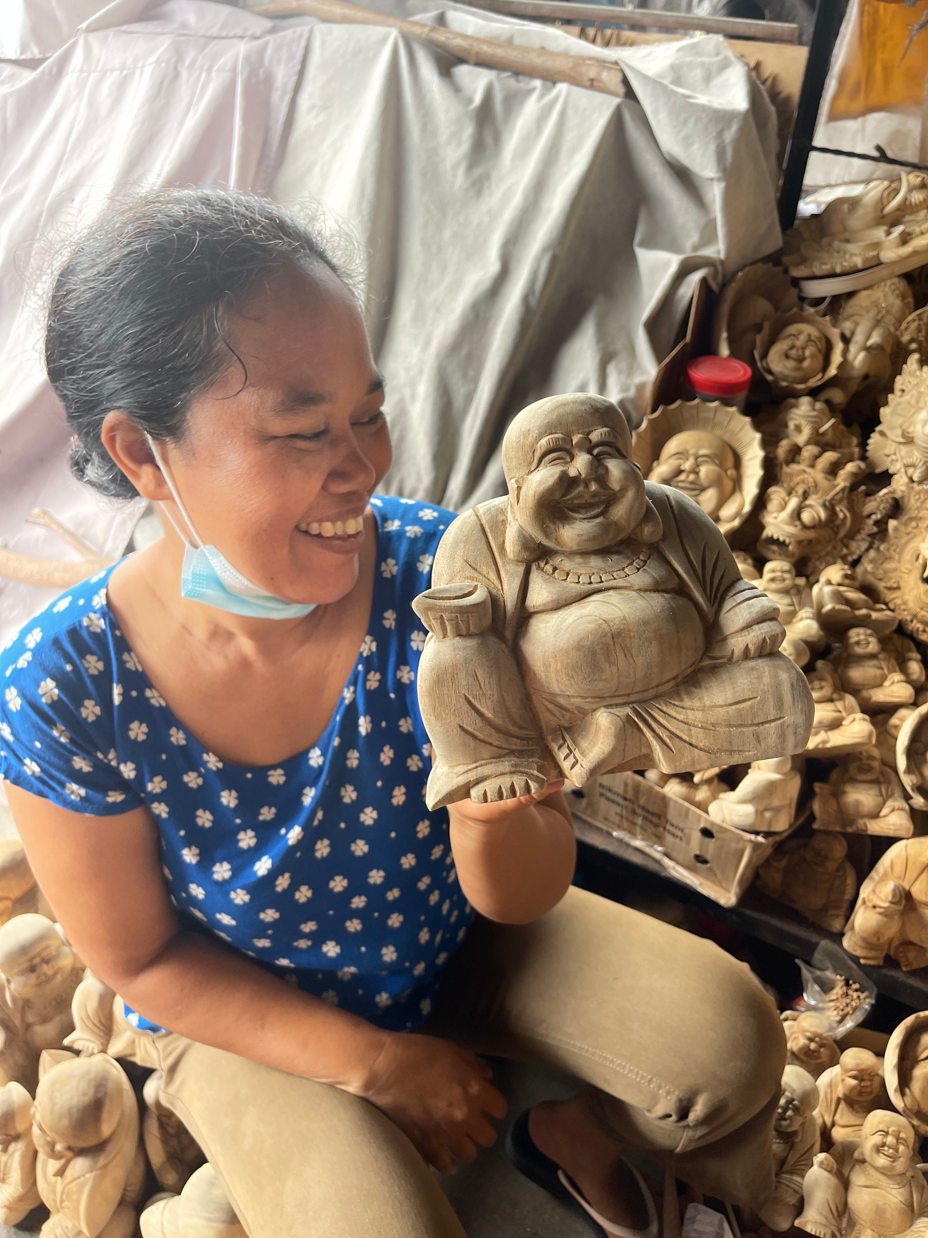 Woman holding handcrafted wooden Buddha from Bali