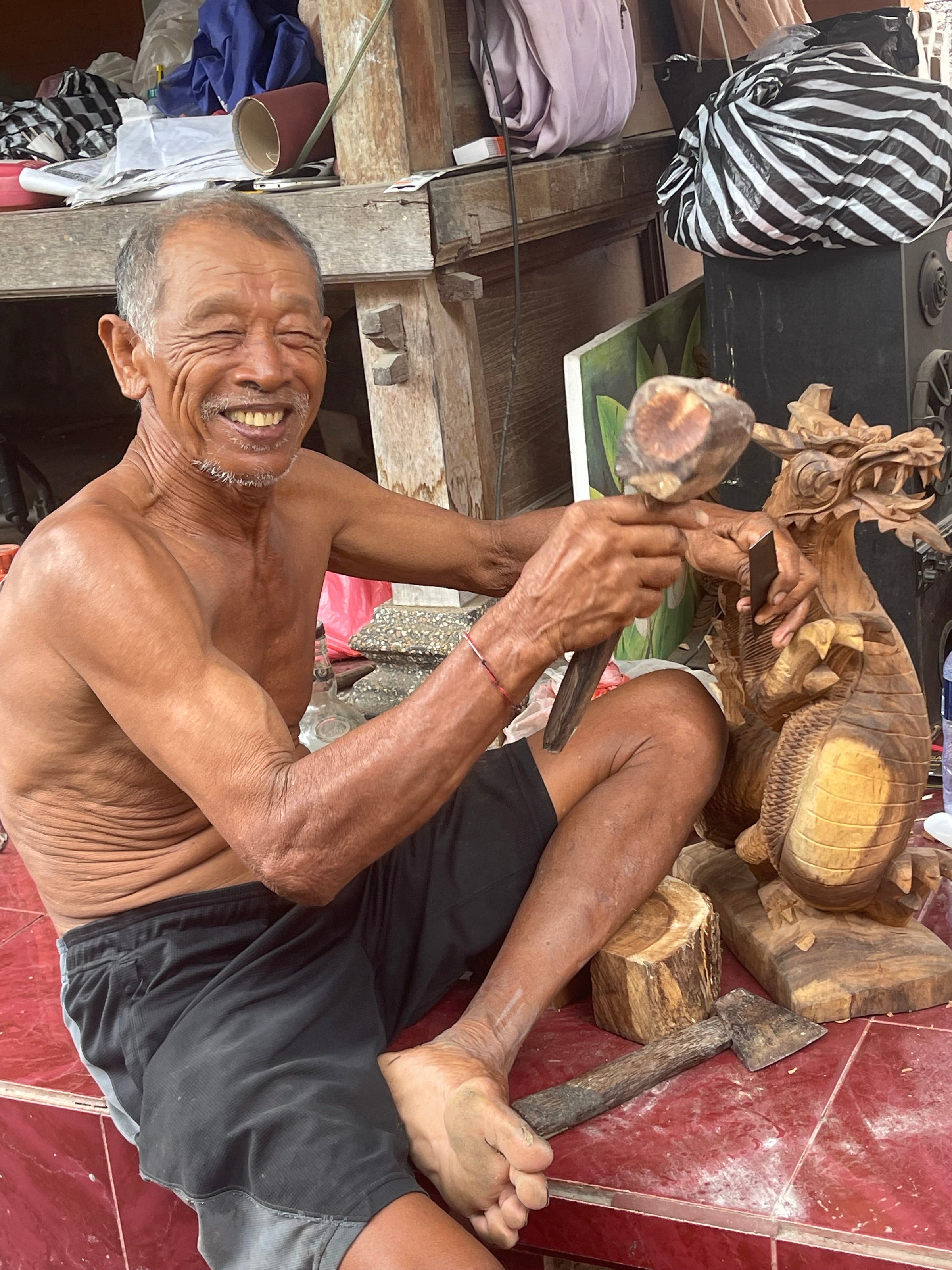 Smiling man carving wooden statue by hand 