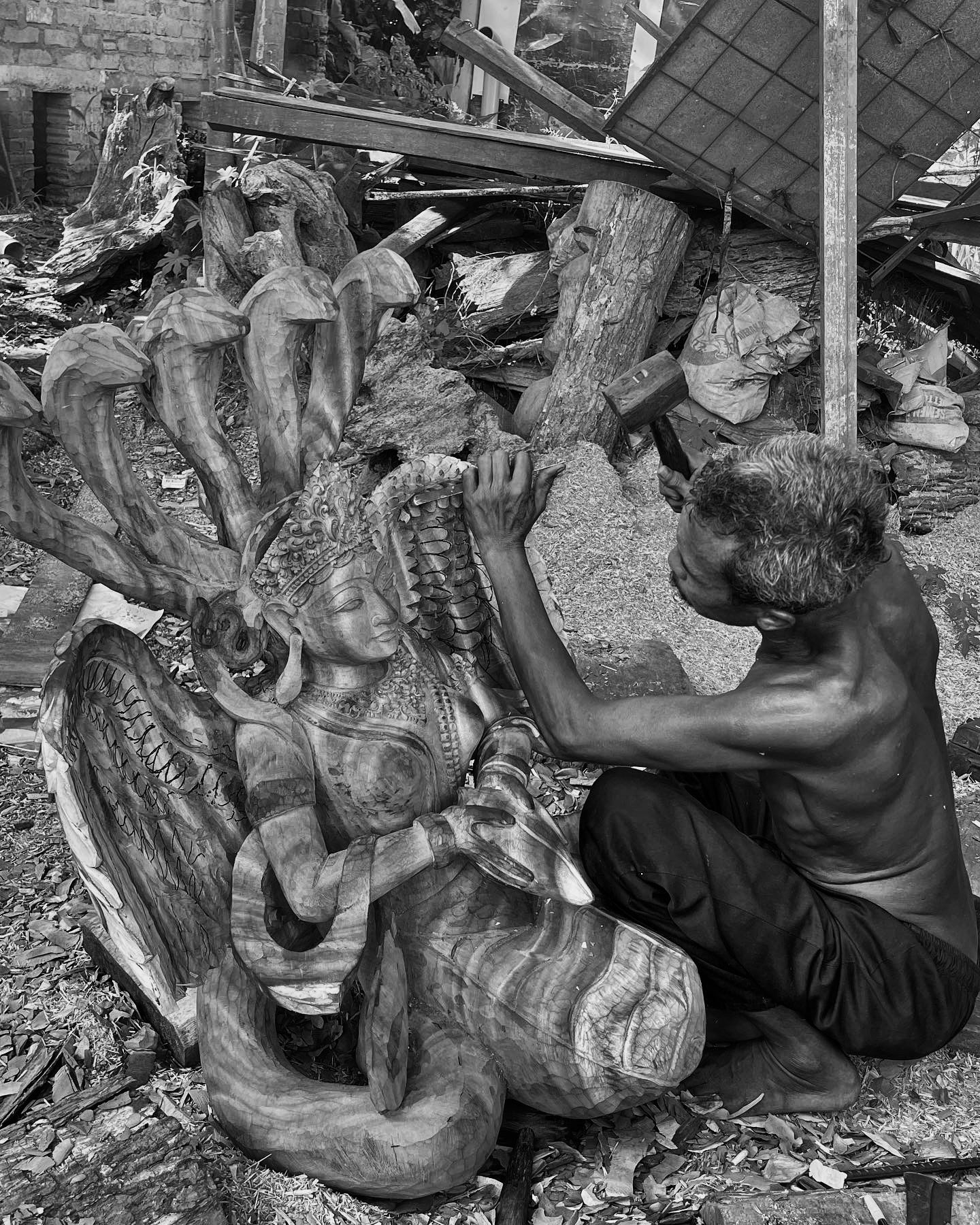 Man handcrafting wooden Buddha statue 